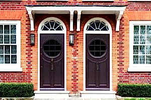 Twin Arched Dark Doors in Red Brick Wall with White Details